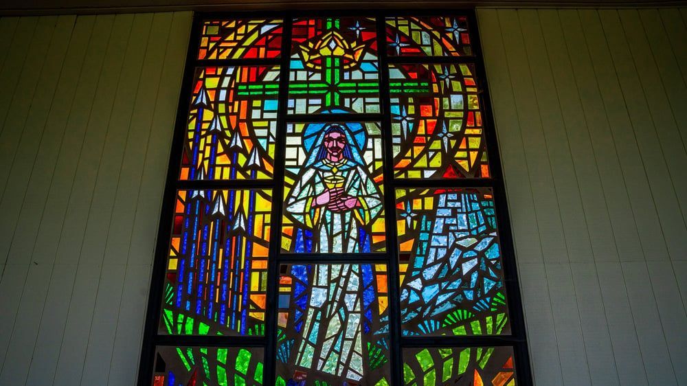 Stained-glass window with a robed figure in a colorful geometric church design