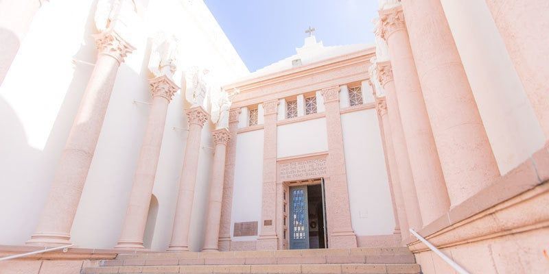 Sunlit neoclassical building entrance with tall white columns and a central doorway