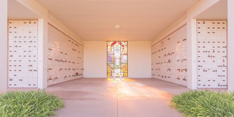 Modern white chapel corridor with stained-glass window and sunlight