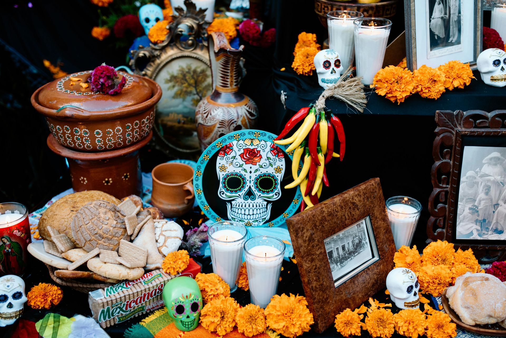 Day of the Dead altar with skull decorations, candles, marigolds, bread, and colorful offerings