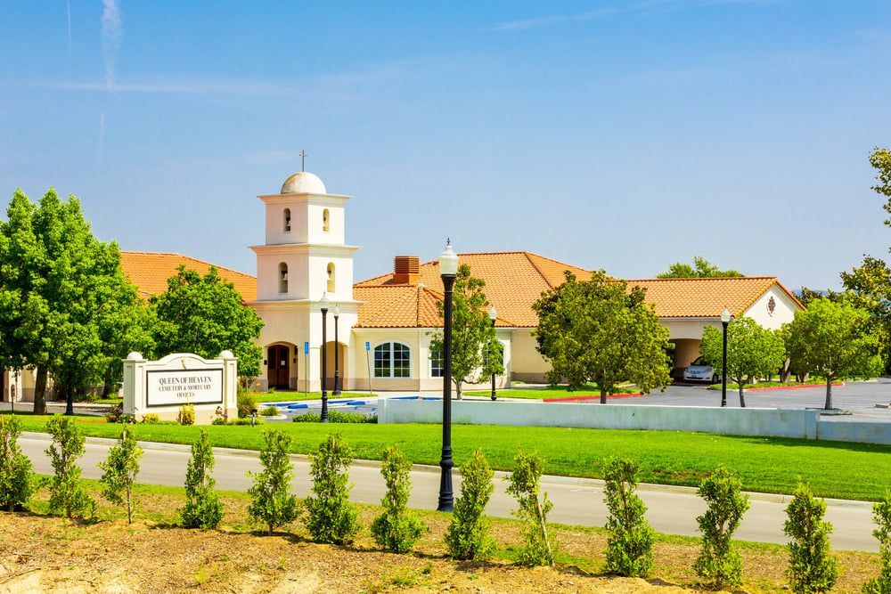 Bright white church with a bell tower, green lawn, and trees under a blue sky