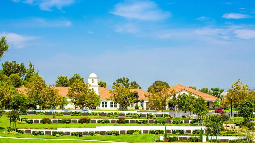 Bright campus with white buildings, red roofs, trees, and landscaped green lawns under a blue sky