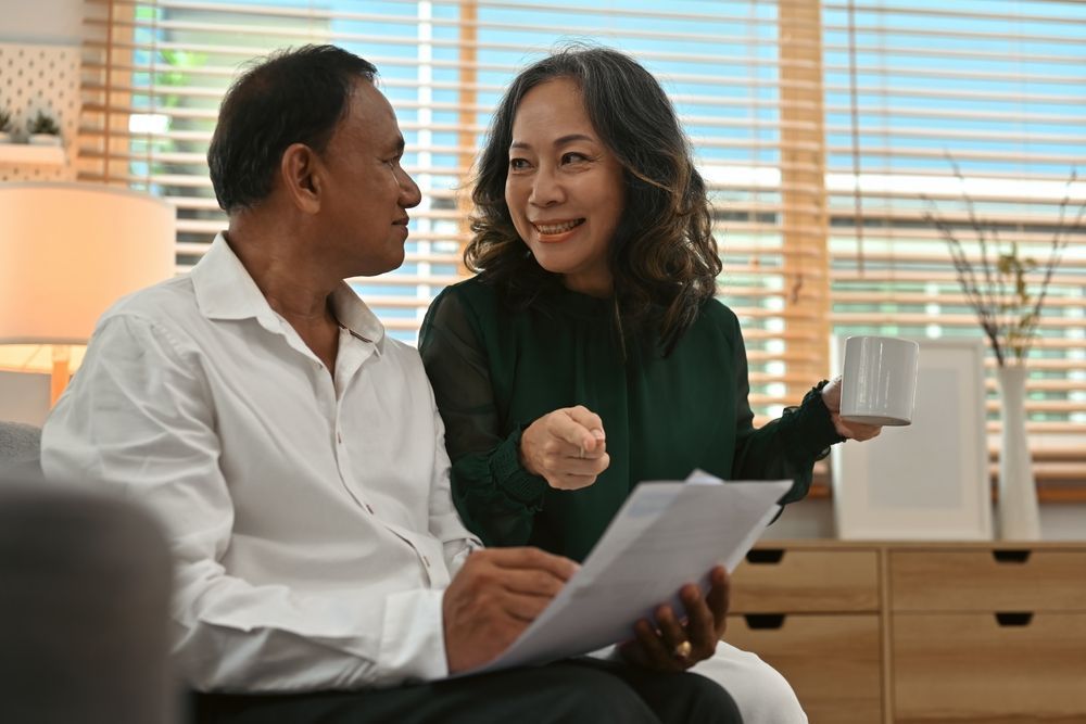 Male and Female couple at home happily looking at brochures or documents. 
