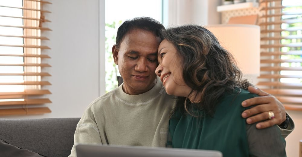 Male and Female couple, sitting on sofa, smiling embrace as if relaxed and relived.