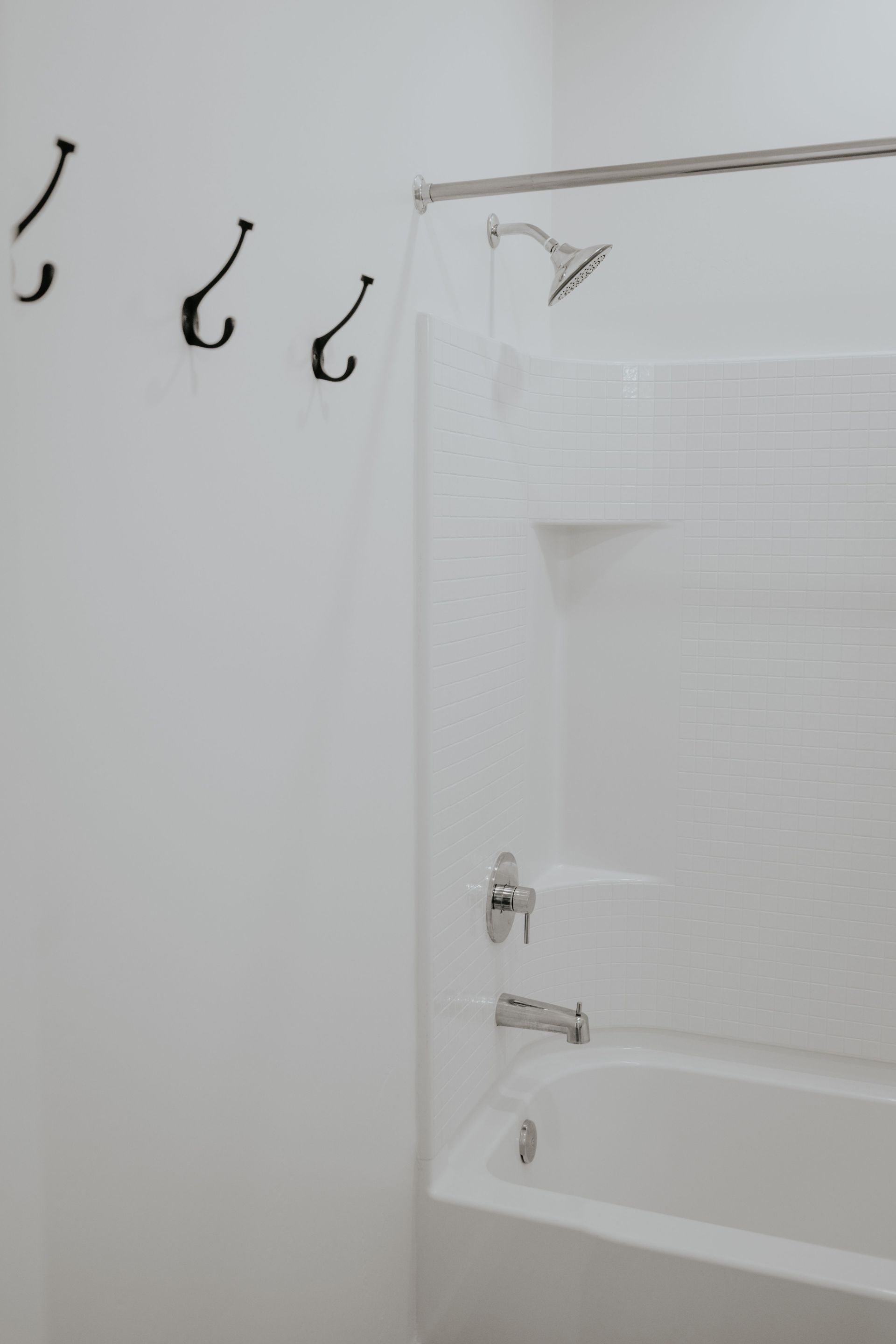 bathroom shower/tub with towel hooks on wall