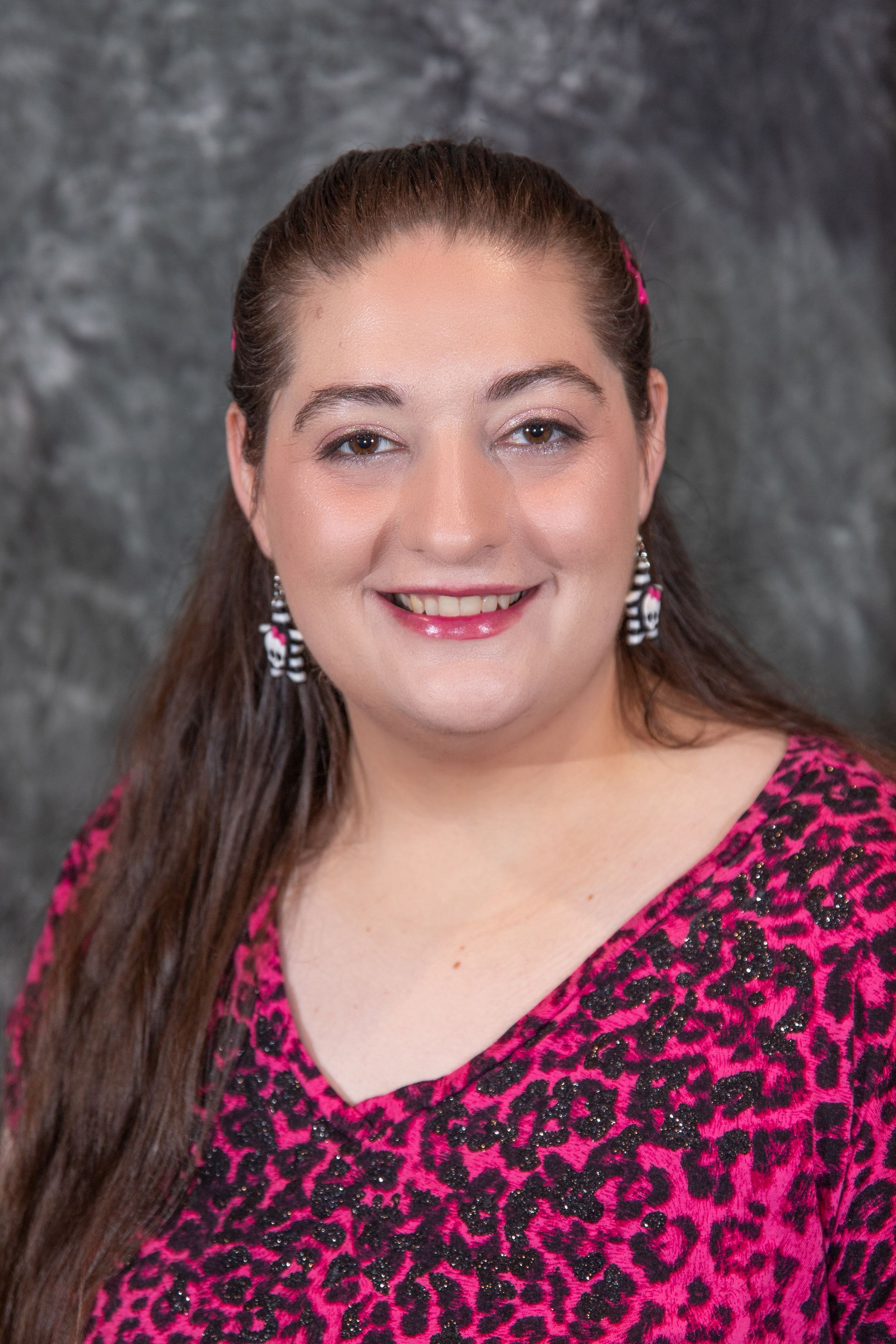 Woman with brown hair smiling, wearing a black and white striped shirt and a black headband.