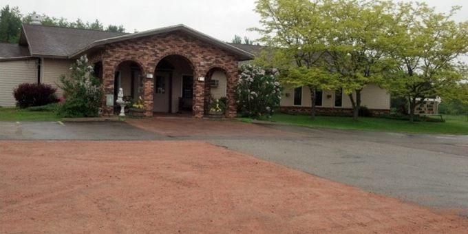 A building with a brick arched entryway and a large tree in front of a wet road.
