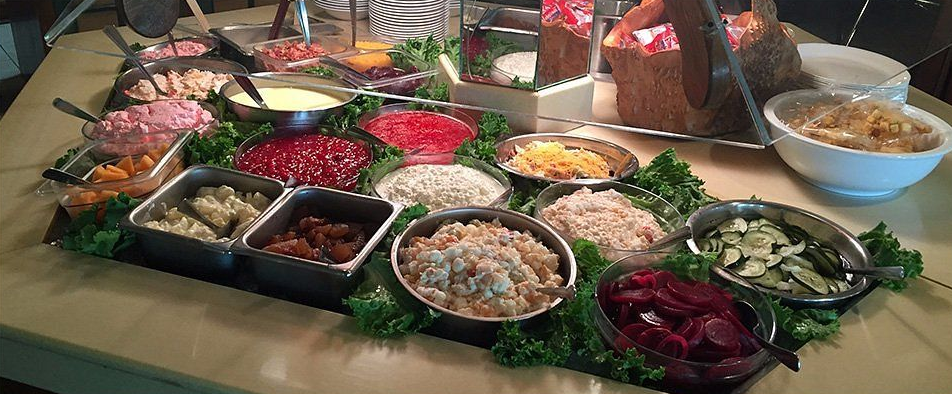 Salad bar with various toppings arranged on a long table.