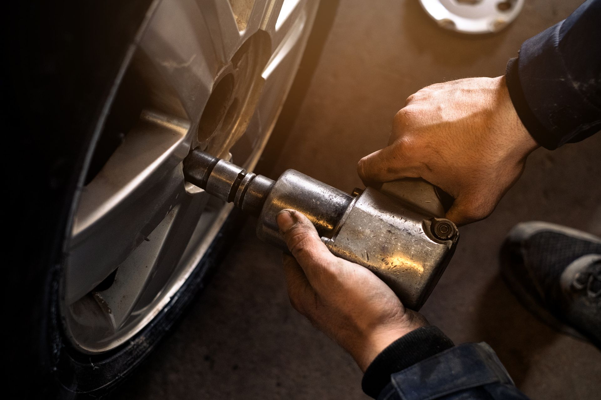 Una persona usa una chiave inglese per allentare i dadi delle ruote di un'auto.