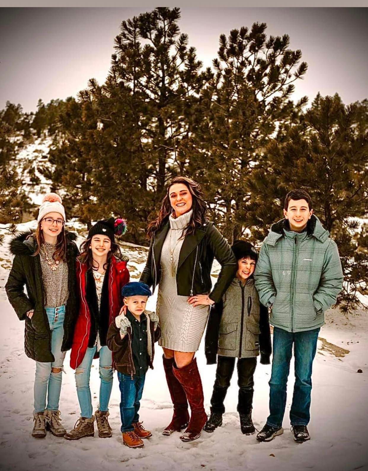 Woman and five children pose in snowy setting.