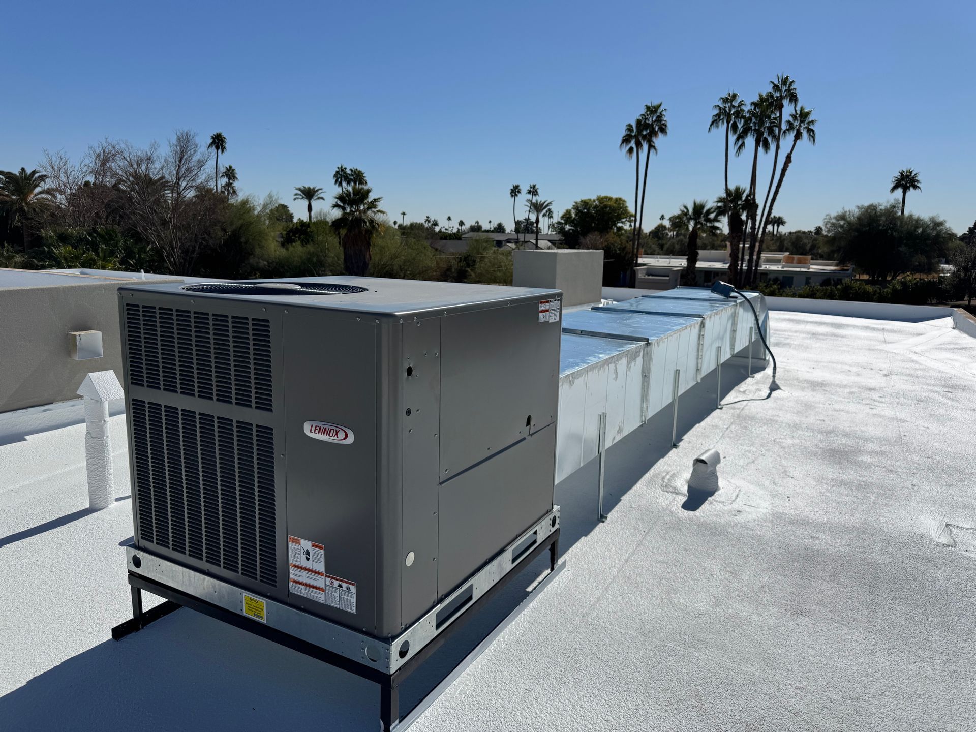 An air conditioner is sitting on top of a white roof