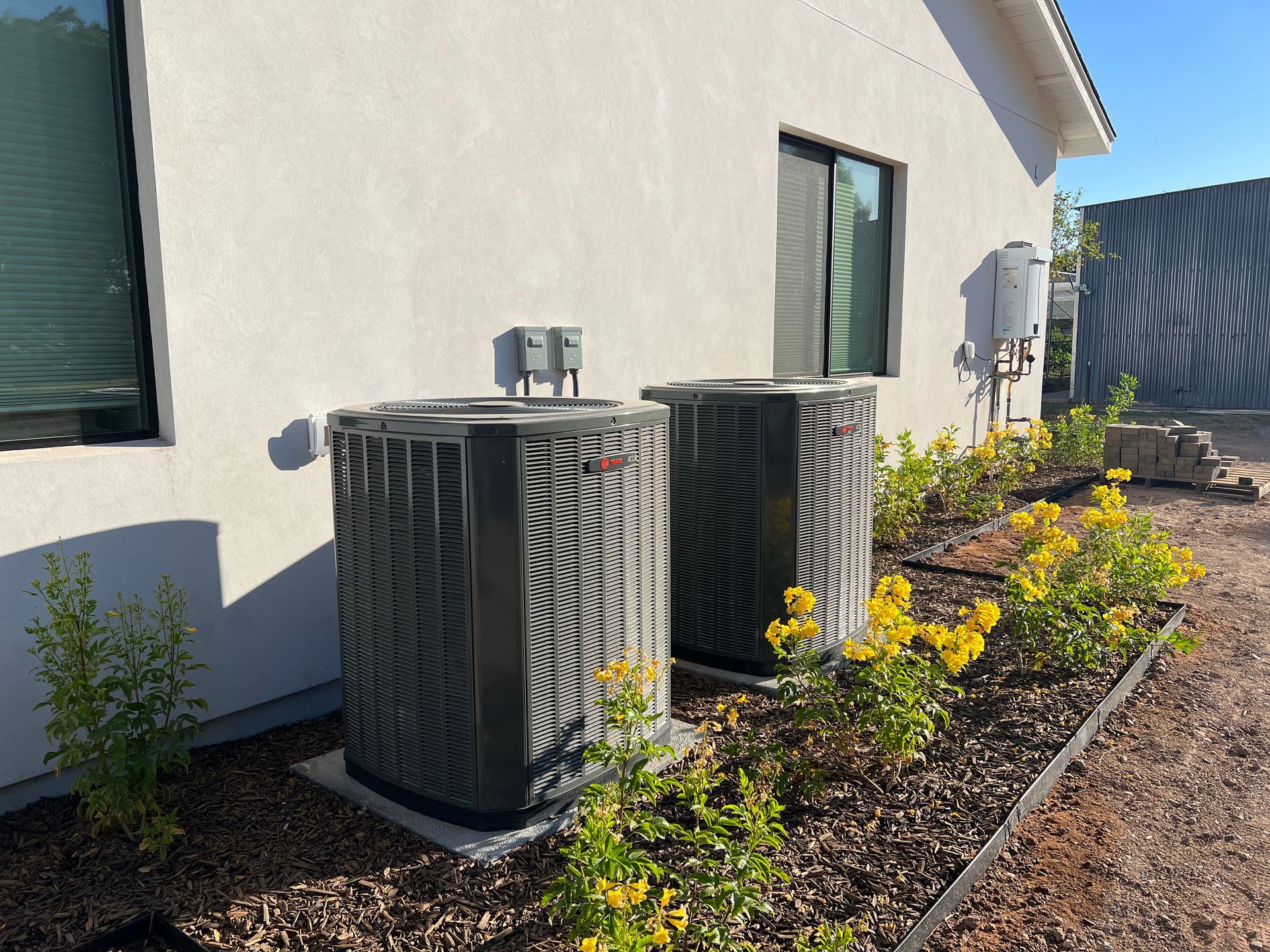 Two air conditioners are sitting on the side of a house.
