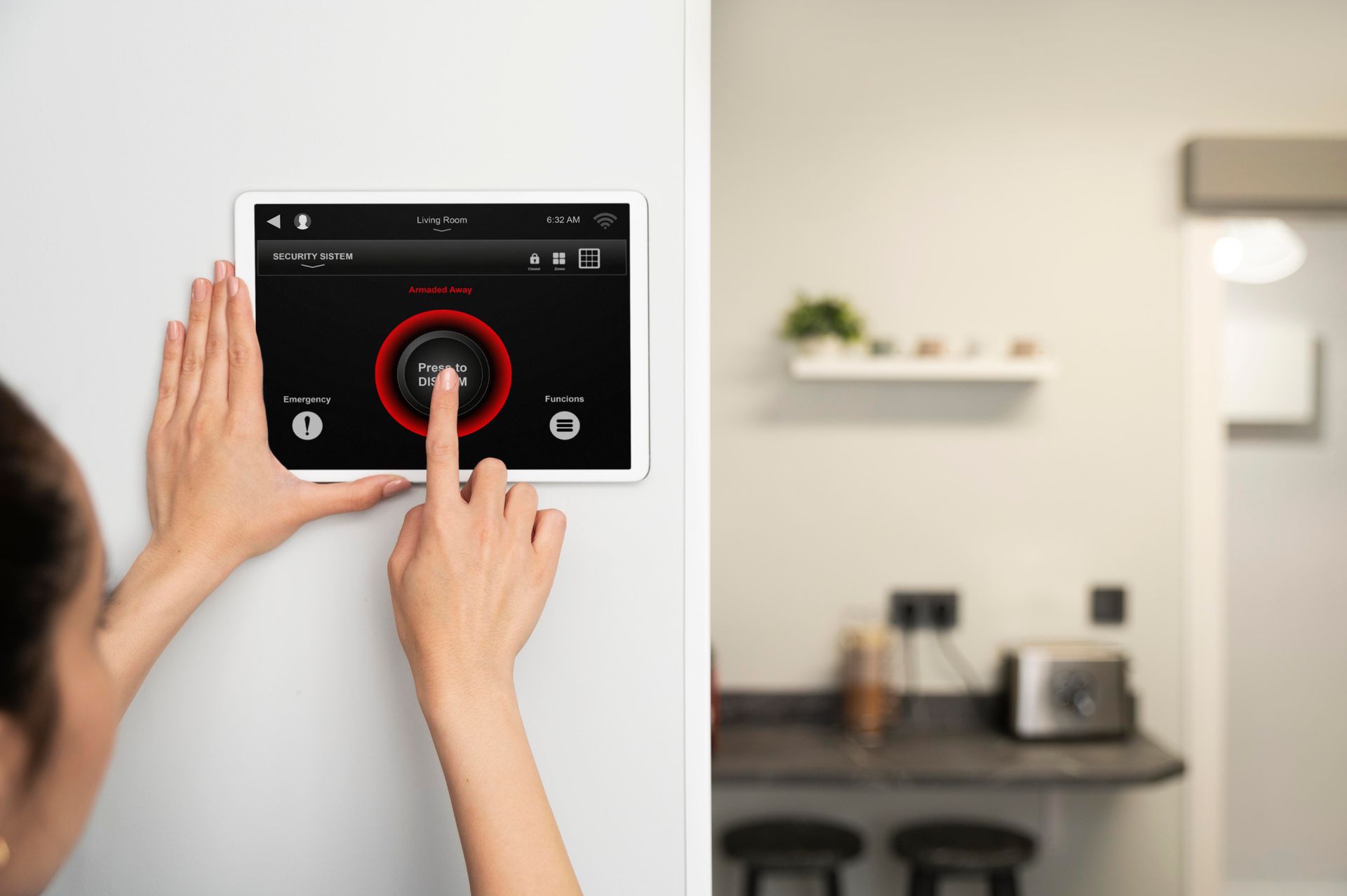 Hands using a wall-mounted touchscreen thermostat in a modern kitchen.