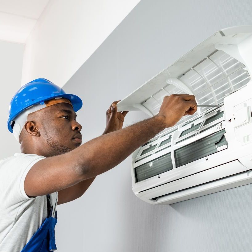 A man is installing an air conditioner on a wall.