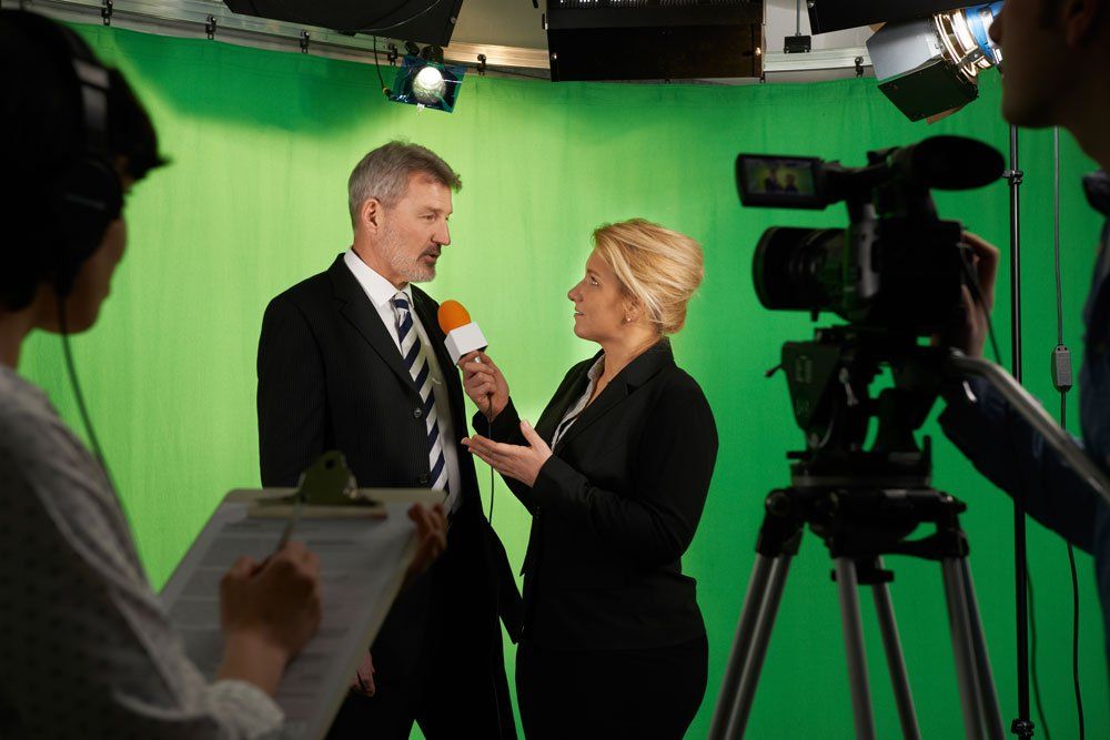 A man and woman are being interviewed on a green screen