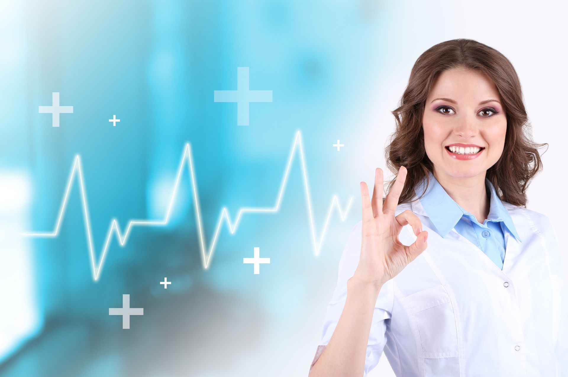 FEMALE DOCTOR GIVING AN OK SIGN a female doctor giving an ok sign in front of a heartbeat graph, representing the close relationship DEZINES has with large global medical brands