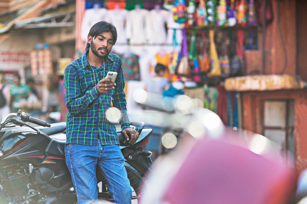 A man standing next to a motorcycle looking at his phone