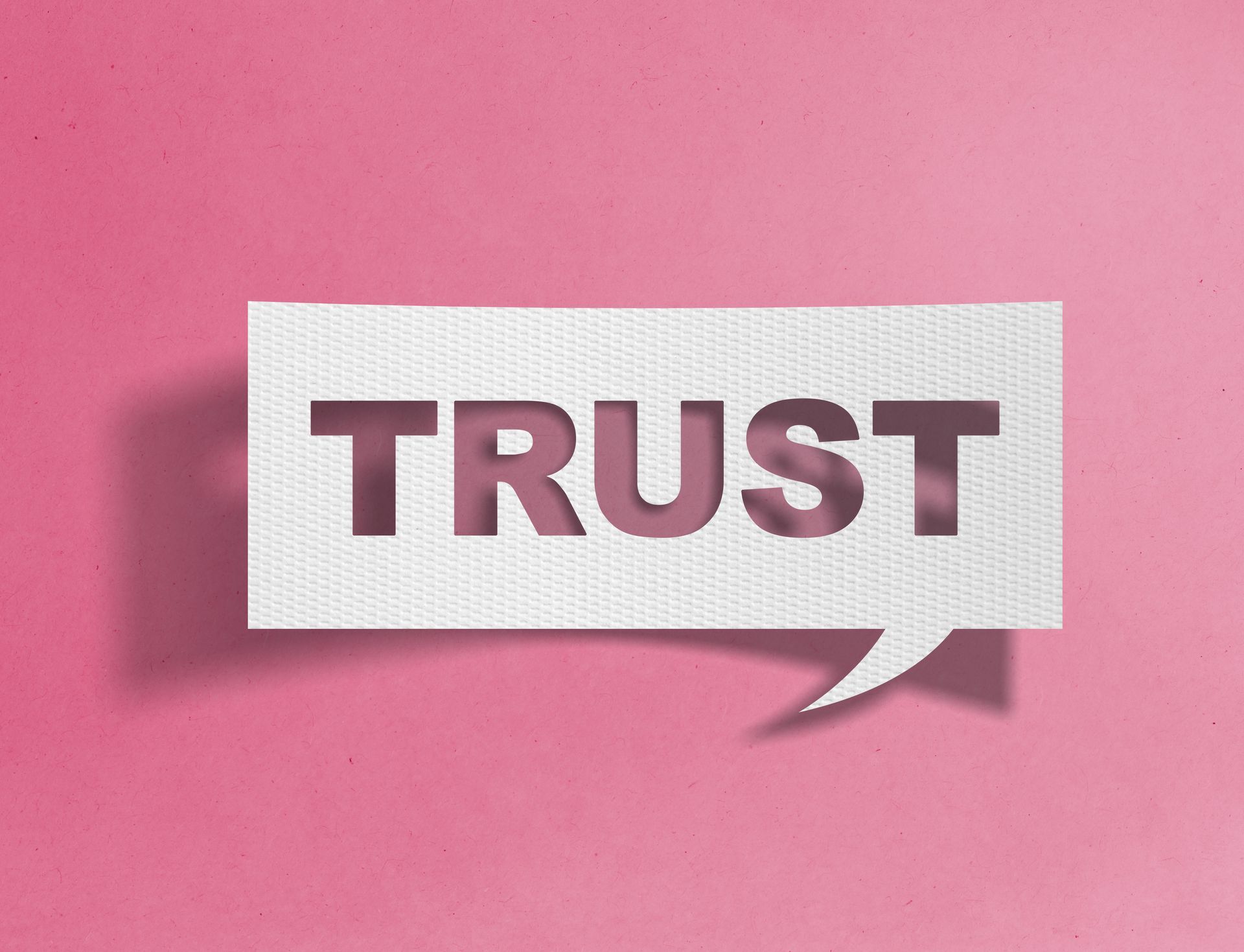 “TRUST” in bold letters on a white speech-bubble shape against a pink background