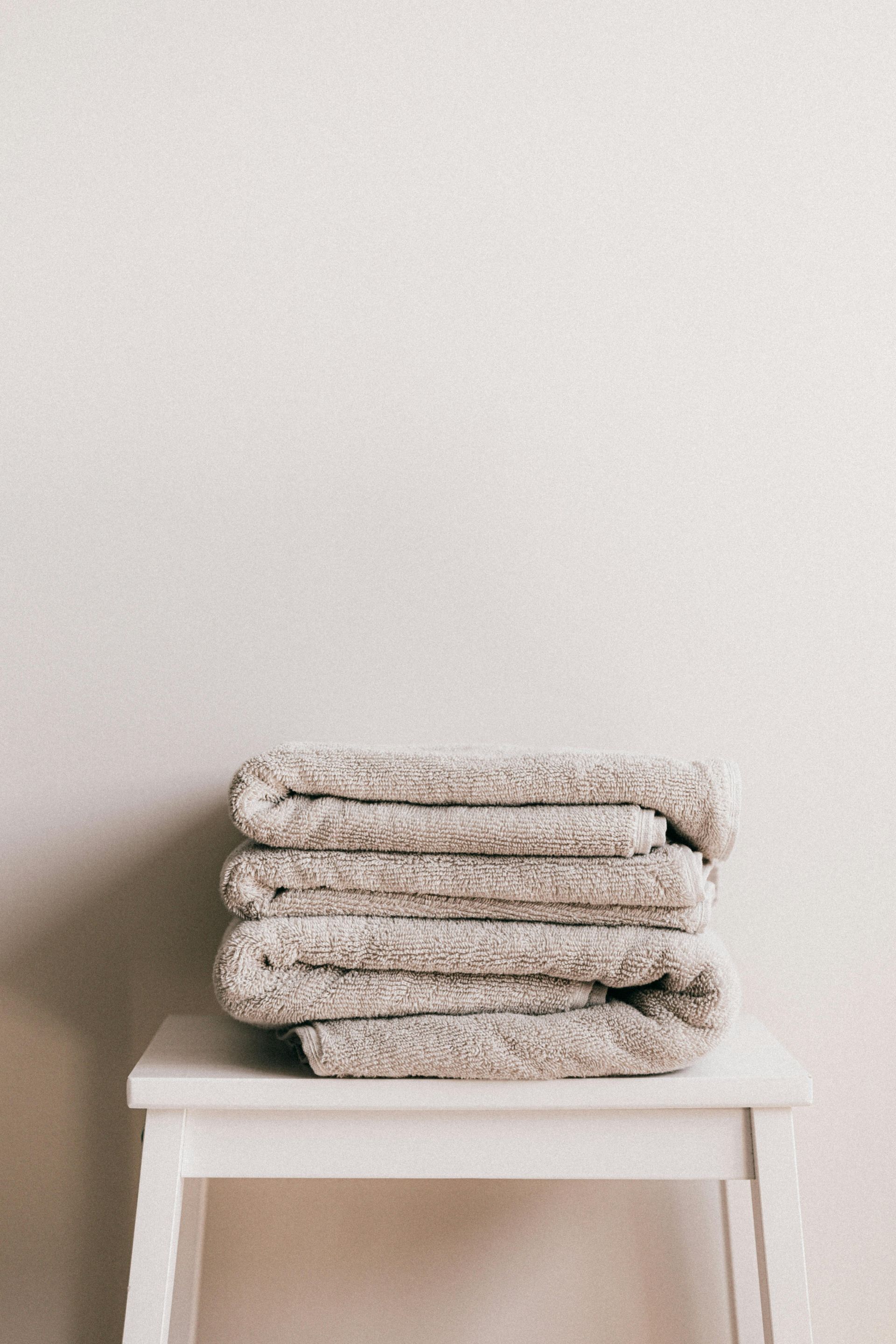 A stack of towels is sitting on a white stool.