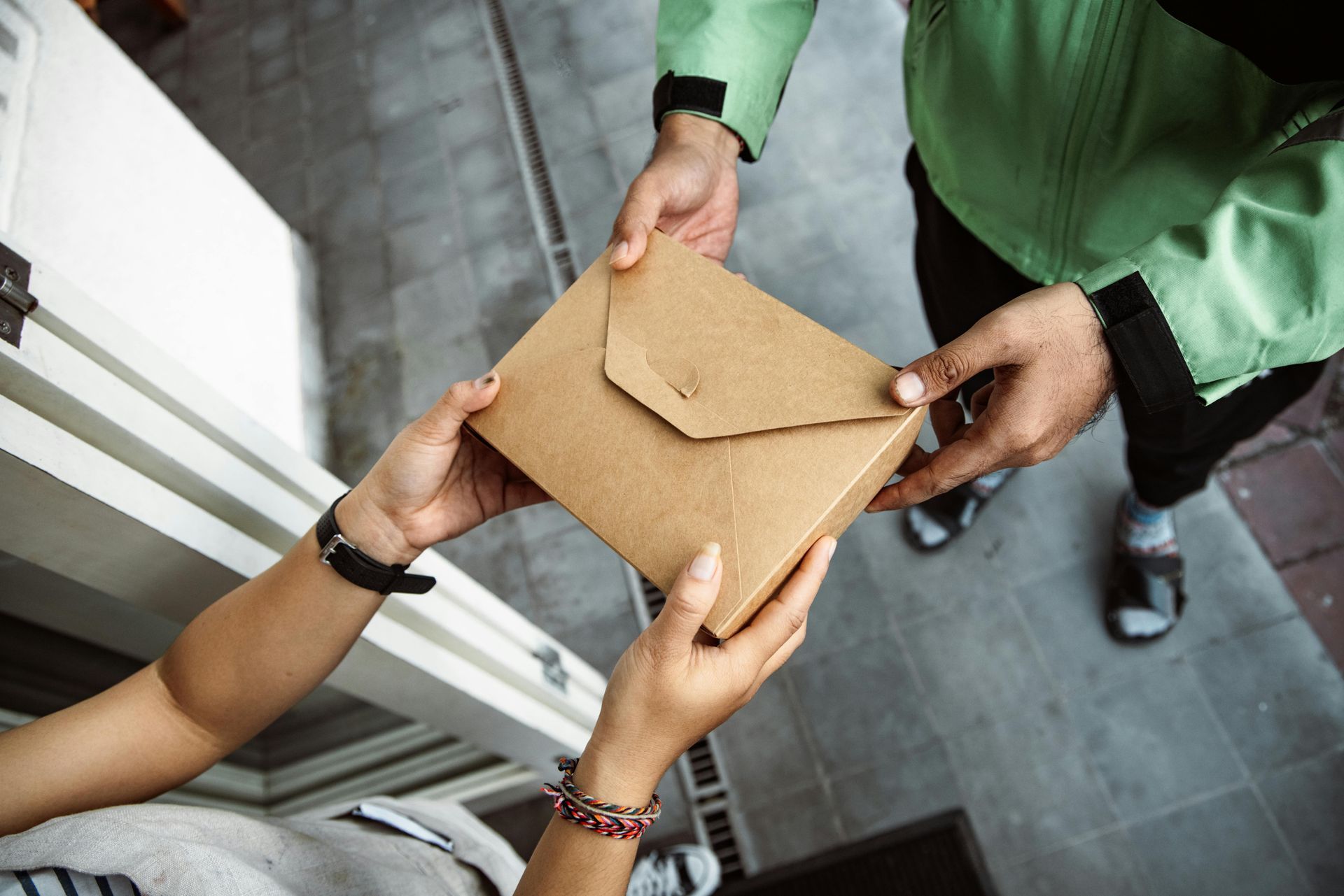 Person handing a brown package to another person.