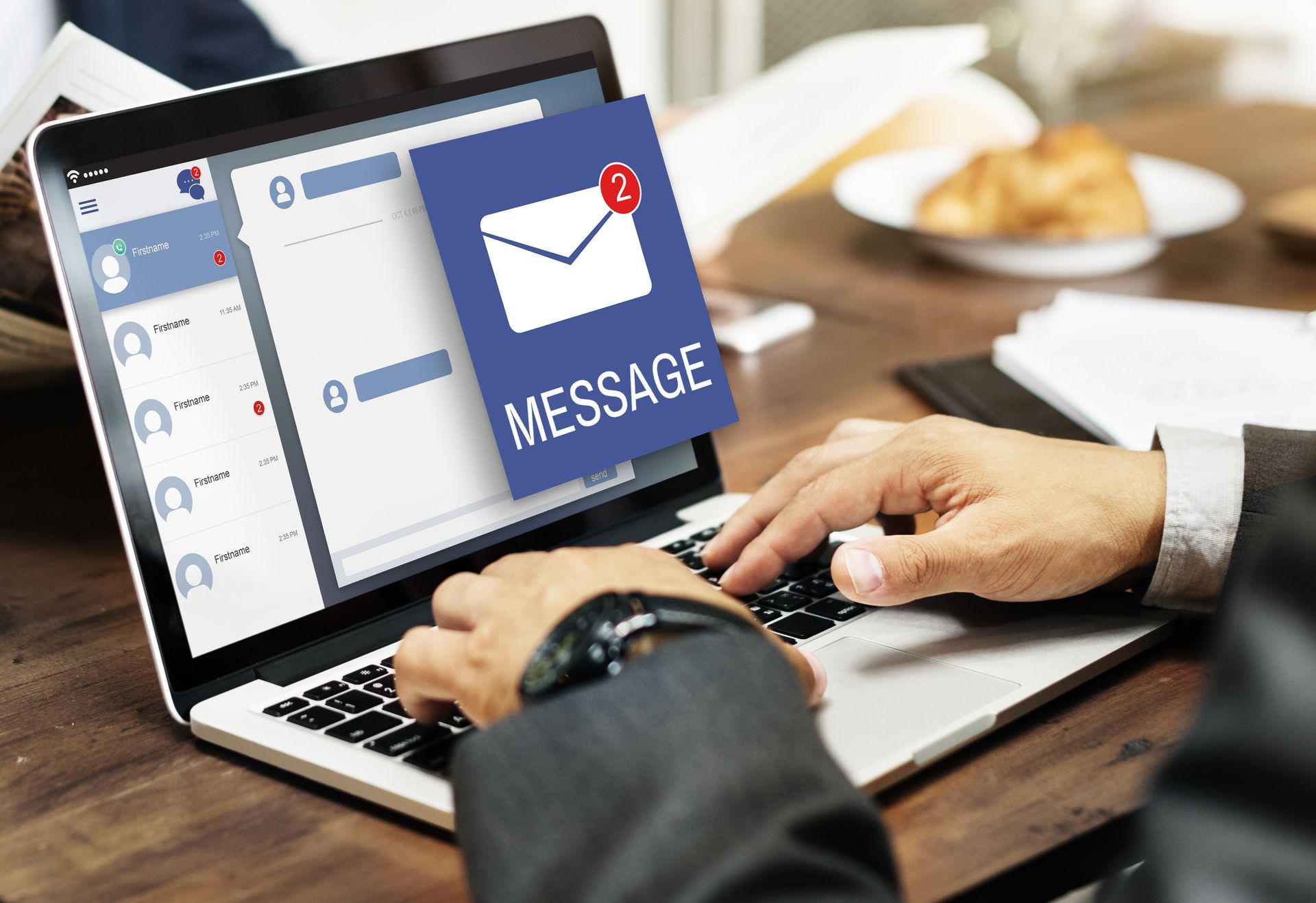 Person typing on laptop, receiving two new message notifications on screen.