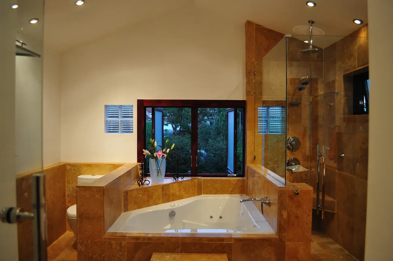 Modern bathroom with a large soaking tub, glass shower, and warm wood tile accents.