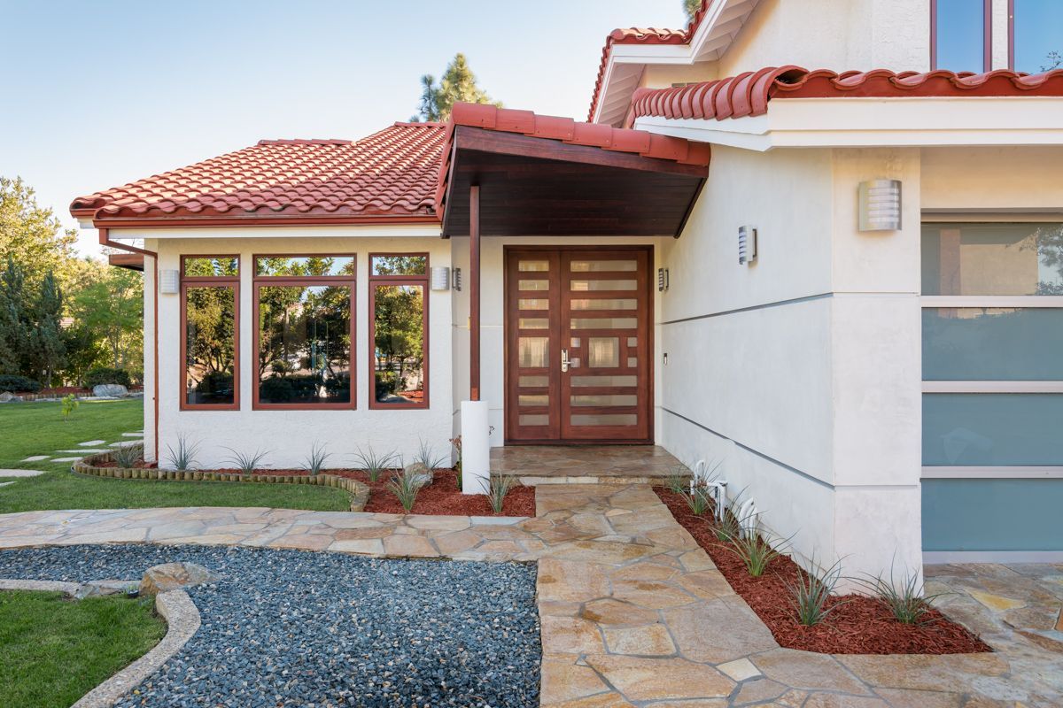 Front view of a modern house with a red tile roof, stone walkway, and small front porch
