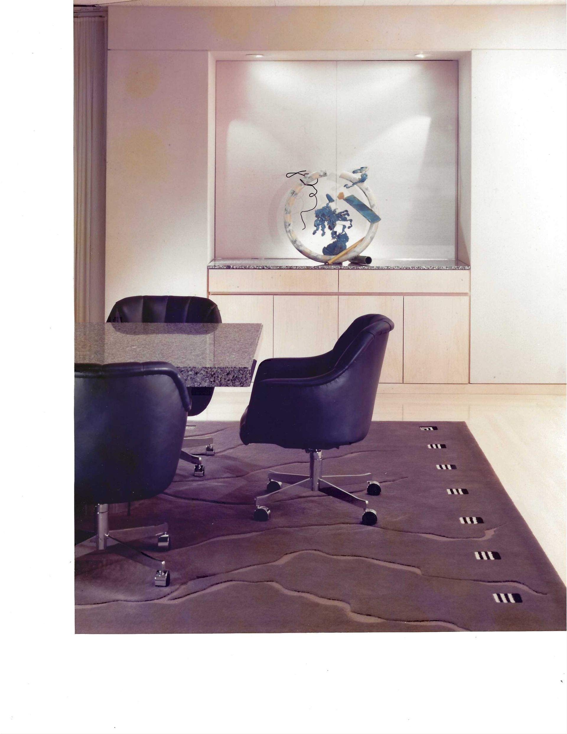 Modern office conference room with glass table, black chairs, and a globe display on the back wall