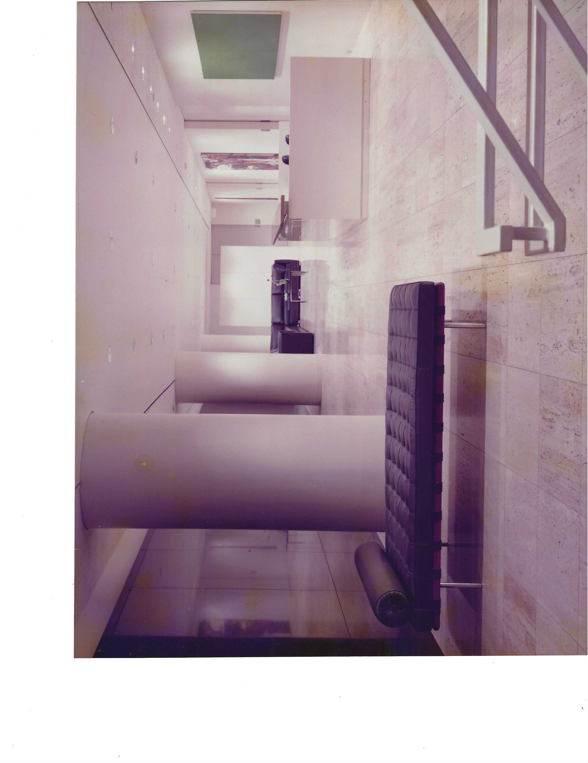Indoor industrial hallway with large white cylindrical ducts and overhead piping