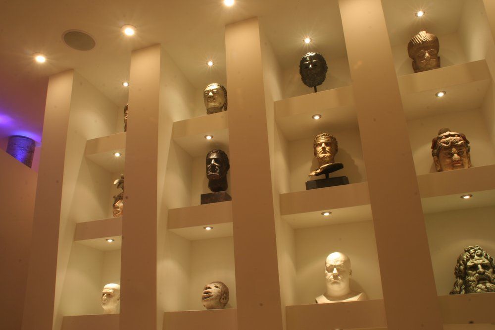 Shelves of small sculpted busts displayed in a warmly lit museum-like wall niche