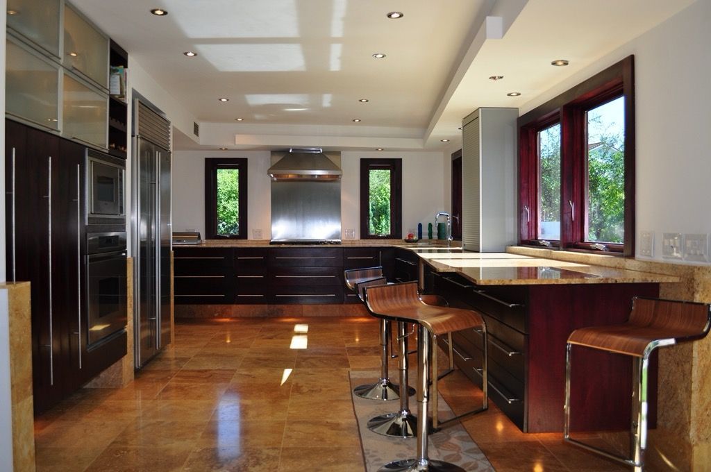 Modern kitchen with dark wood cabinets, island bar stools, and polished hardwood floors
