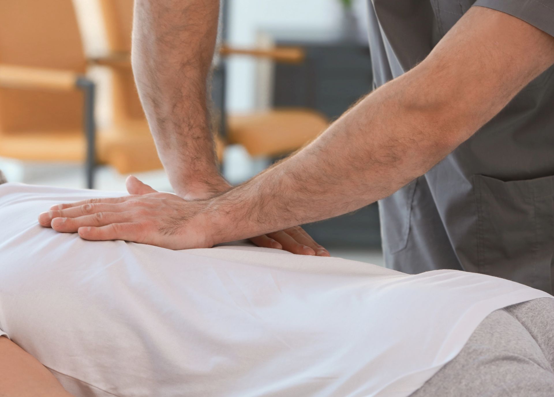 Chiropractor pressing hands on a client’s back on a table