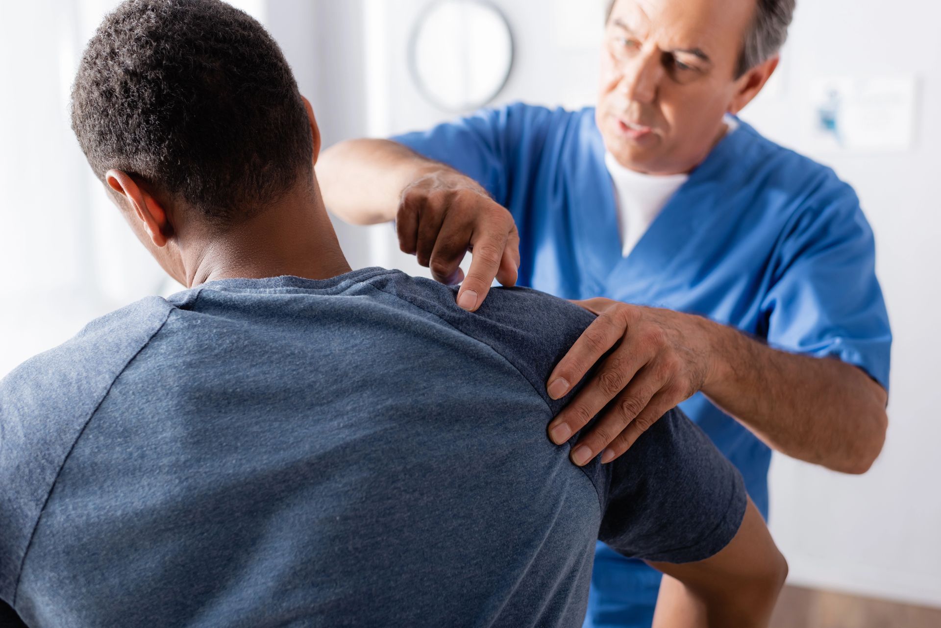 Doctor examining a patient’s shoulder in a bright clinic room