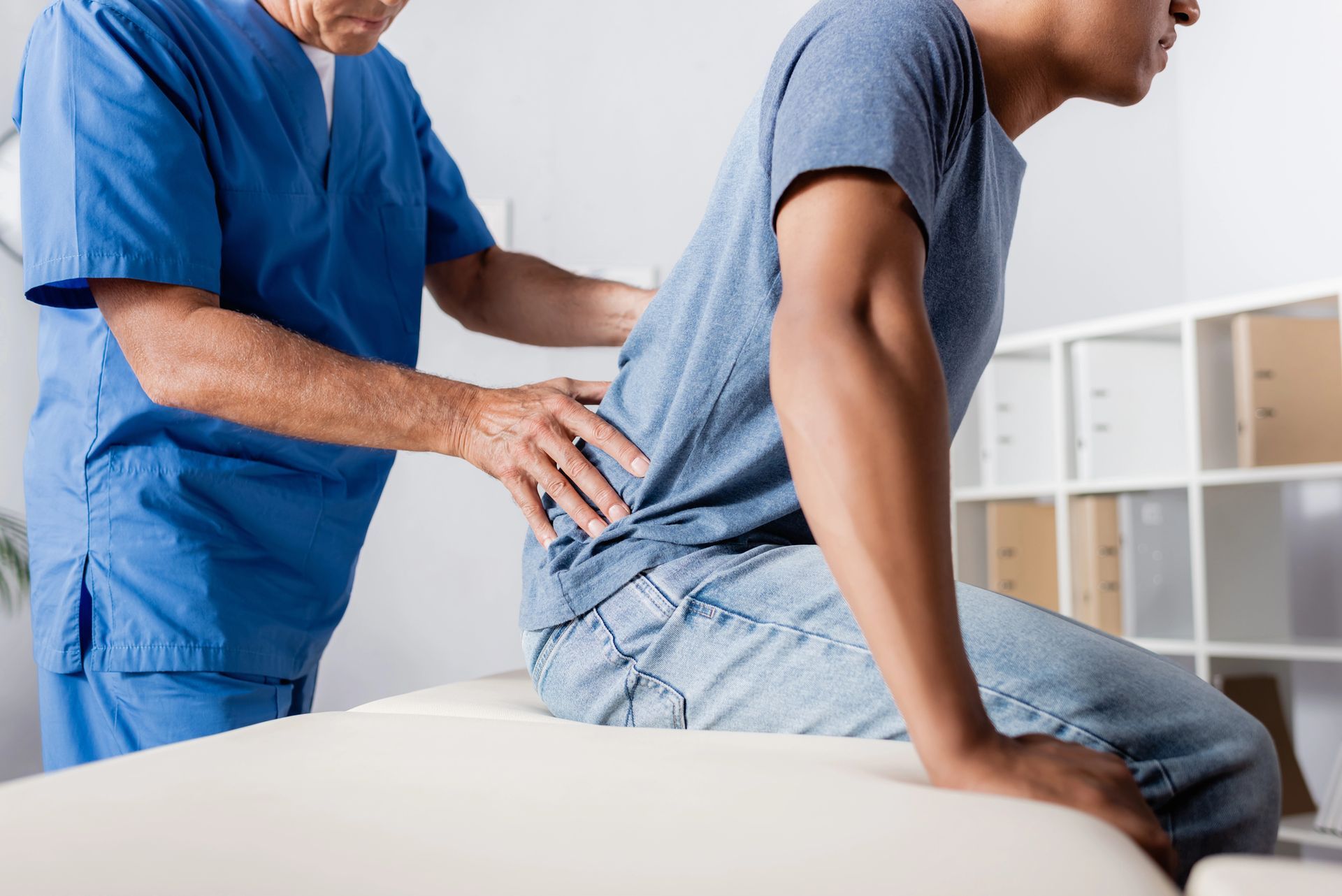 Physical therapist assisting a seated patient with a back massage in a clinic