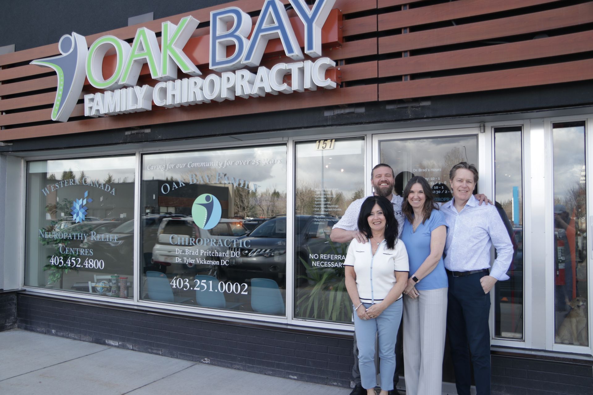 Oak Bay Family Chiropractic office exterior with four people smiling in front. Signage visible.