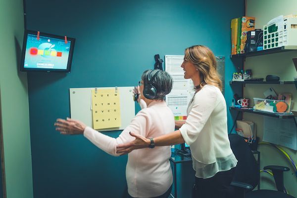 A woman is helping an elderly woman walk in front of a television.
