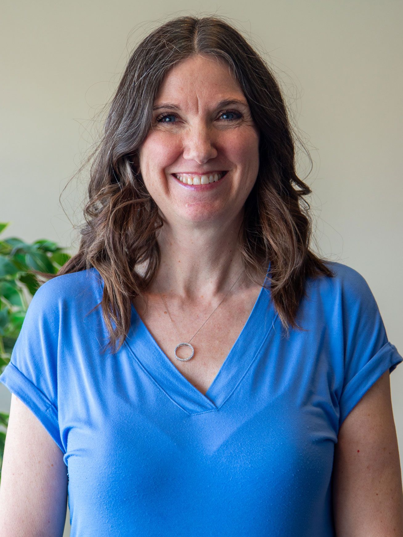 A woman in a blue shirt is smiling for the camera.