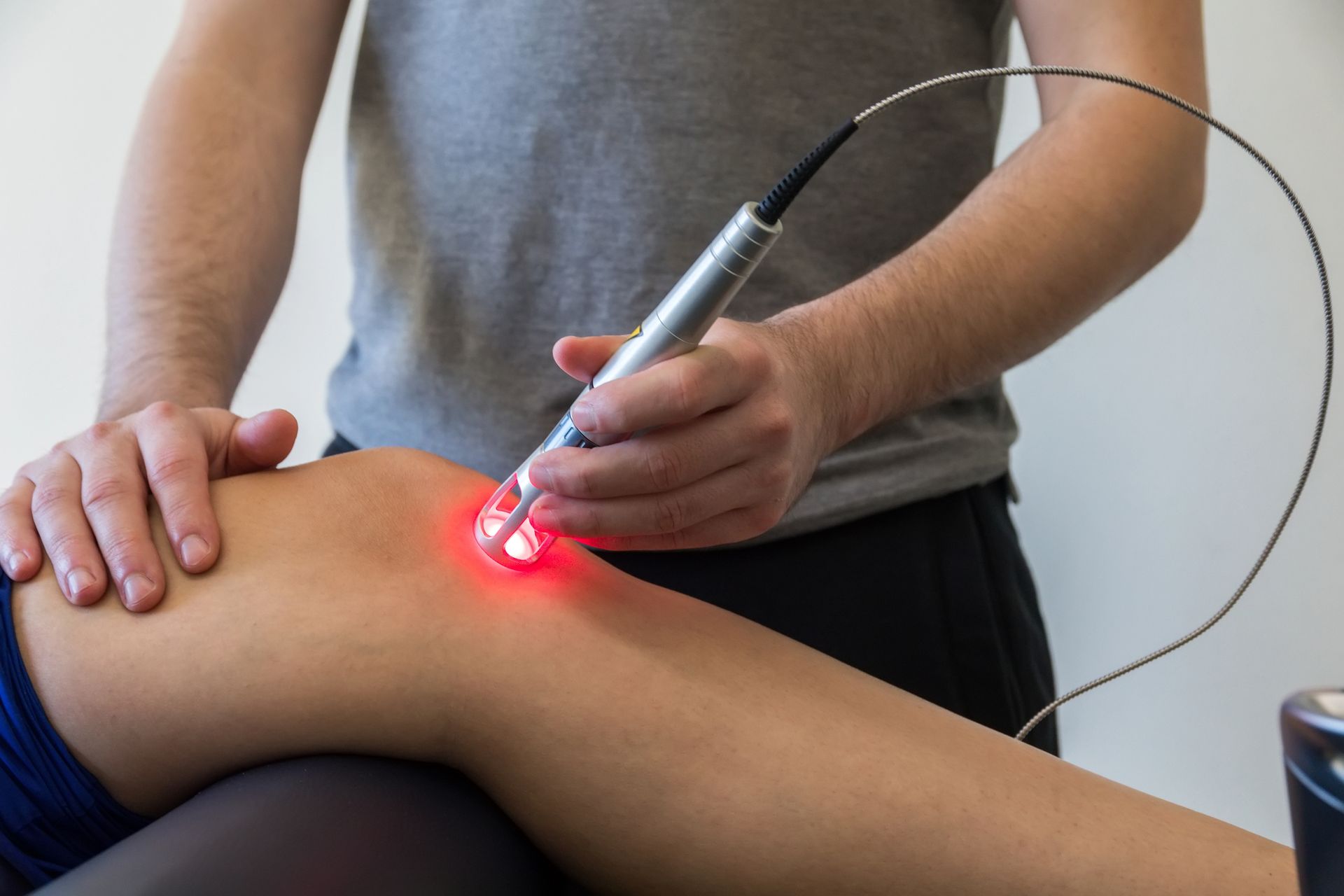 A person is getting cold laser therapy on their knee.