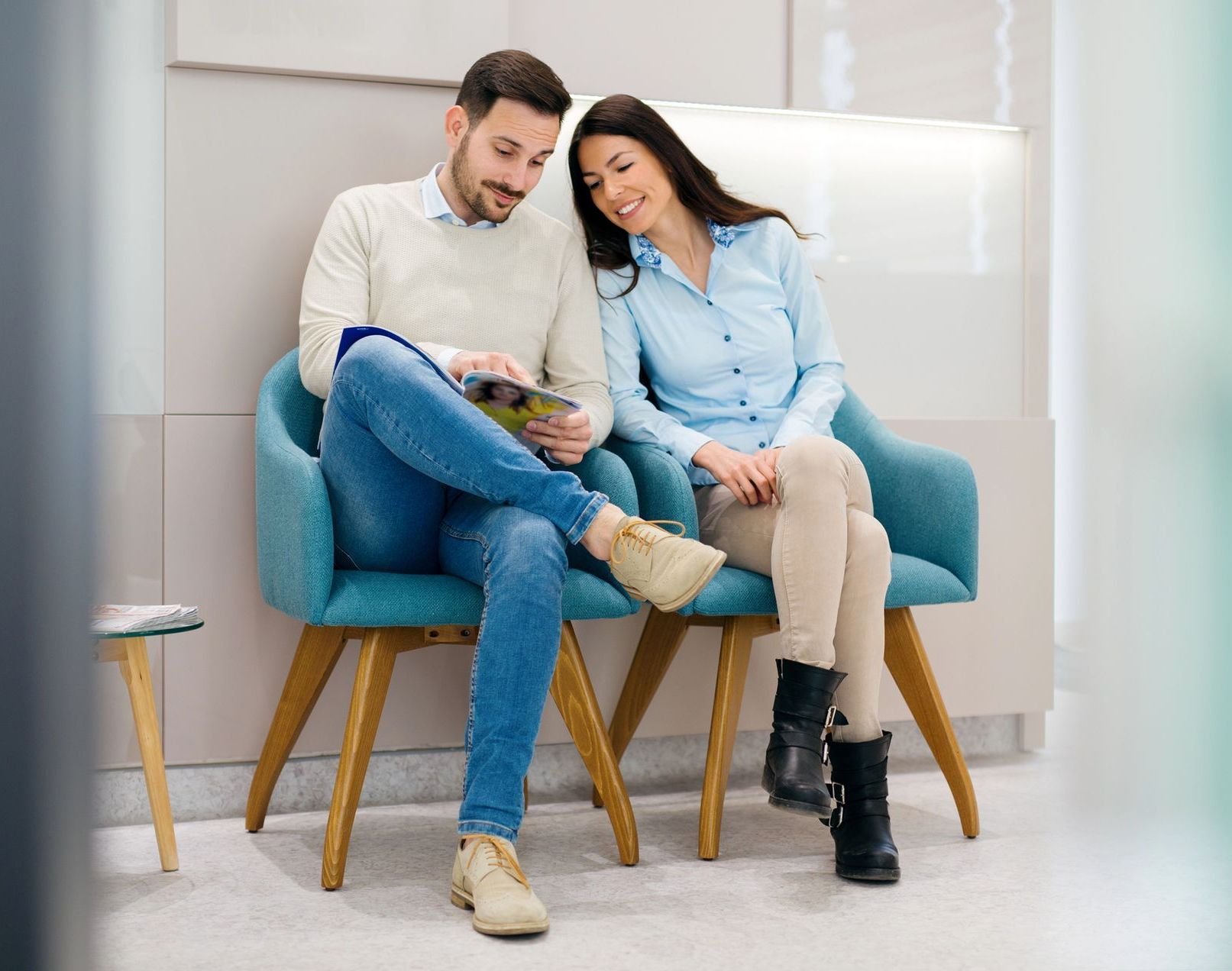 A man and a woman are sitting in chairs in a waiting room.