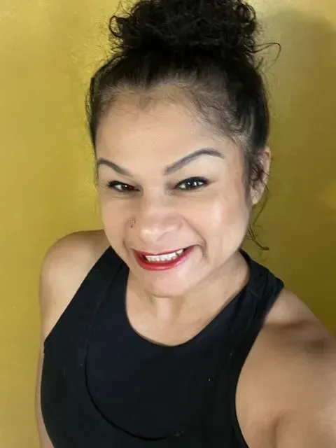 Smiling woman in a black tank top against a yellow background