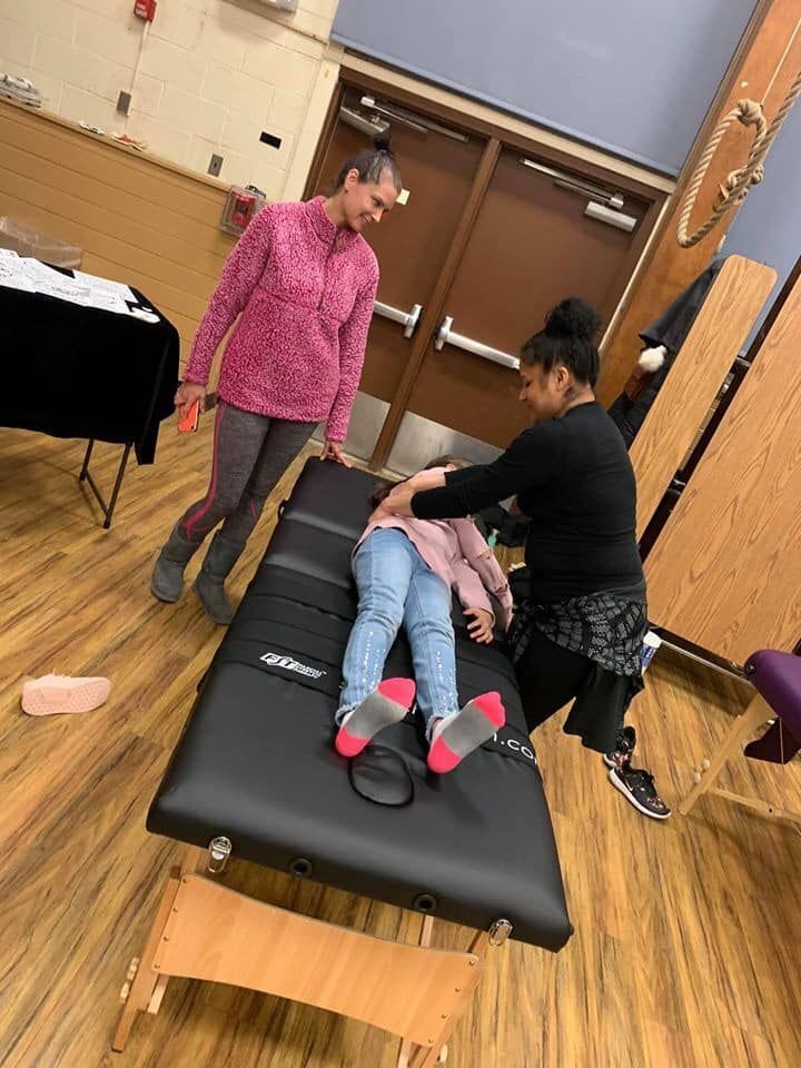 Therapy session with an adult assisting a child on a padded mat in a gym-like room
