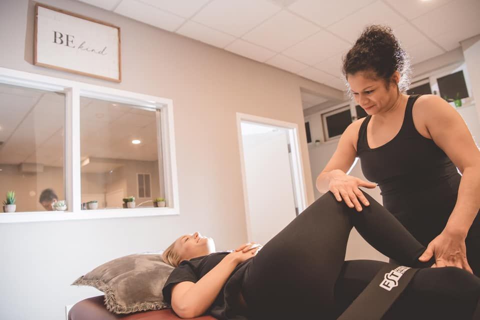 Therapist adjusting a patient’s leg on a treatment table in a bright clinic room