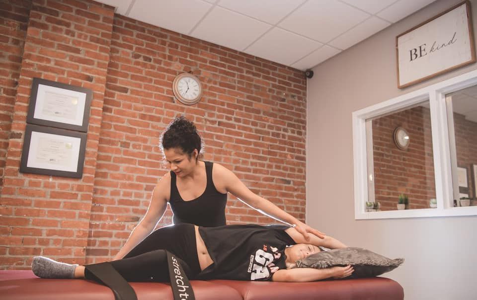 Massage therapist working on a client on a table in a brick-walled treatment room