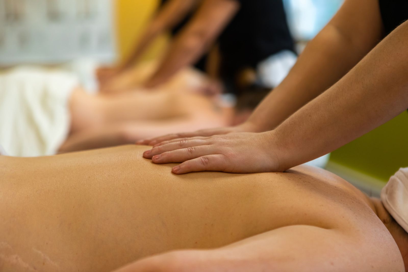 Massage therapist’s hands pressing on a client’s bare back in a spa setting