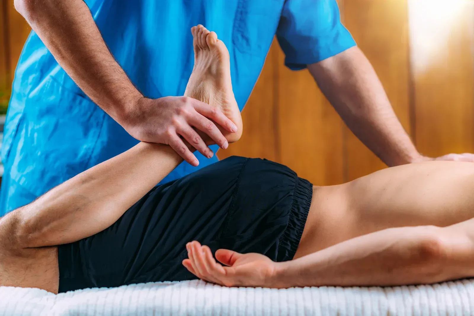 Therapist stretching a person's leg during a massage on a treatment table