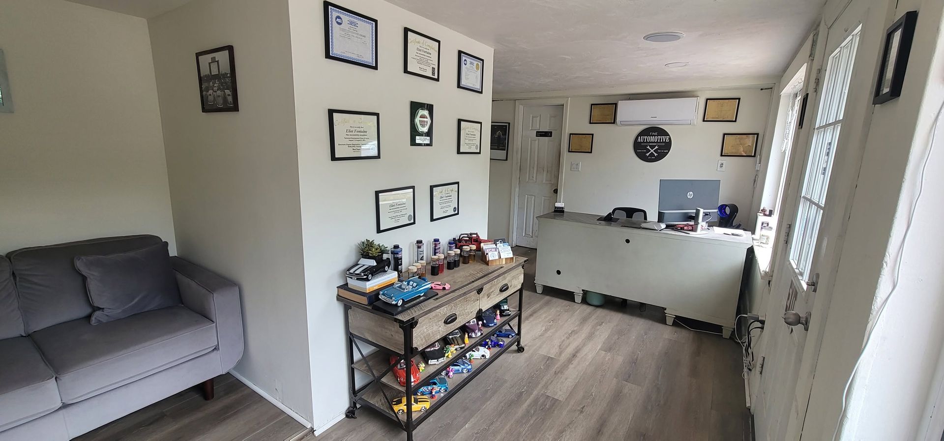 Small apartment living room with gray sofa, framed wall art, and a kitchen in the background | FINE Automotive Services