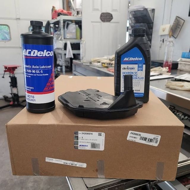 ACDelco auto parts—two bottles and a black filter on a cardboard box in a workshop | FINE Automotive Services
