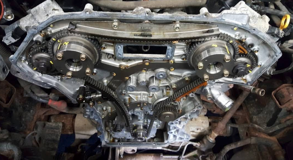 Car engine timing assembly exposed, showing cam gears and timing chain inside a mechanic’s bay | FINE Automotive Services