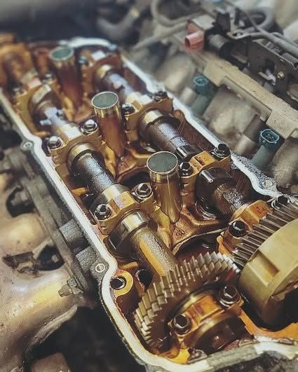Close-up of engine valve train and gears coated in oil inside a metal housing | FINE Automotive Services