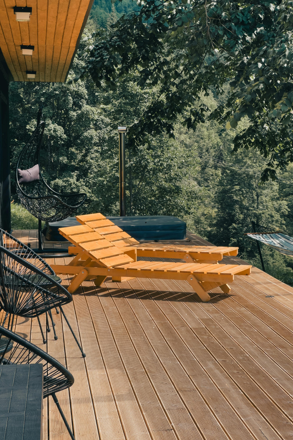 Wooden deck with yellow lounge chairs, surrounded by trees.